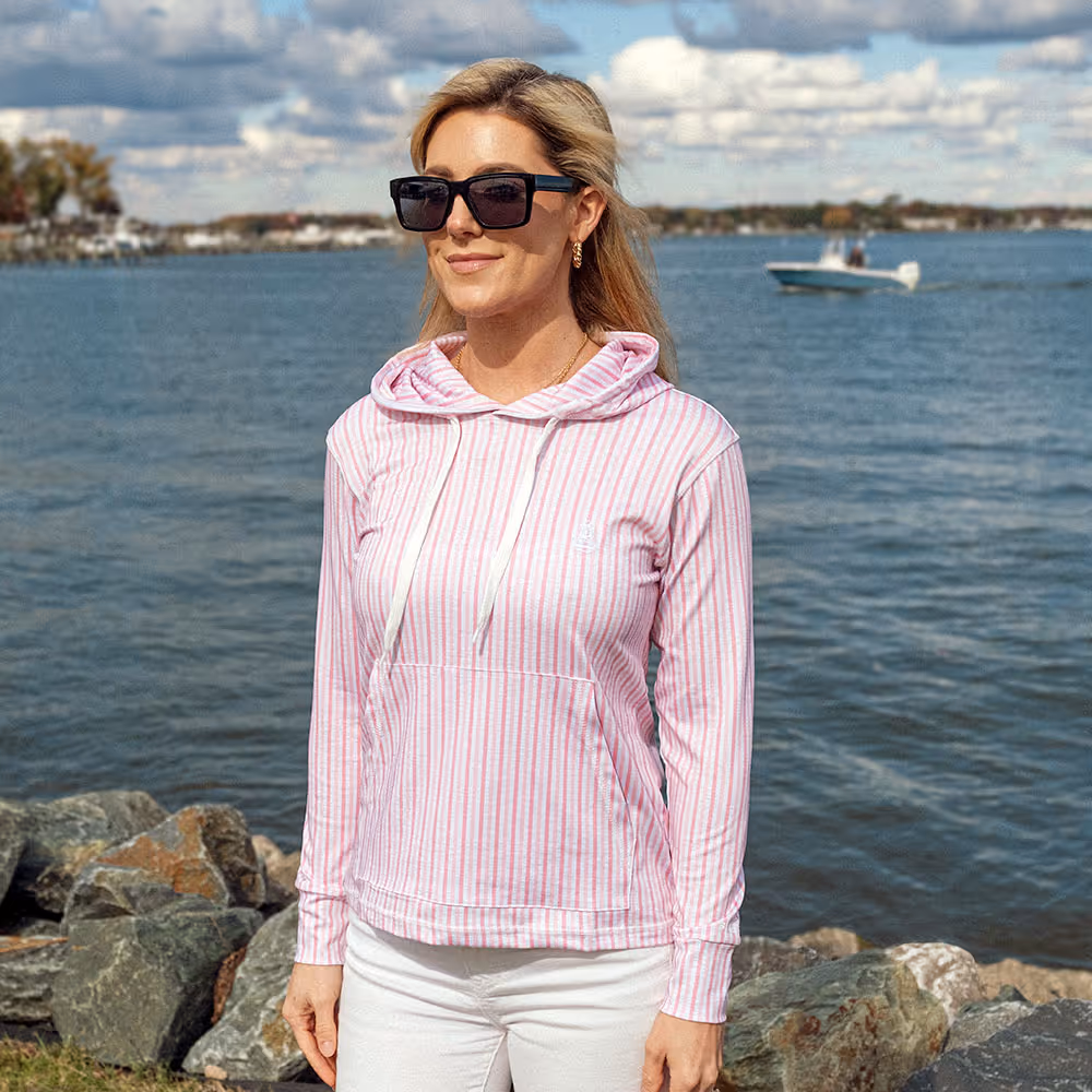 Woman wearing a Performance Hoodie from Six Knots while standing in a marina in front of water
