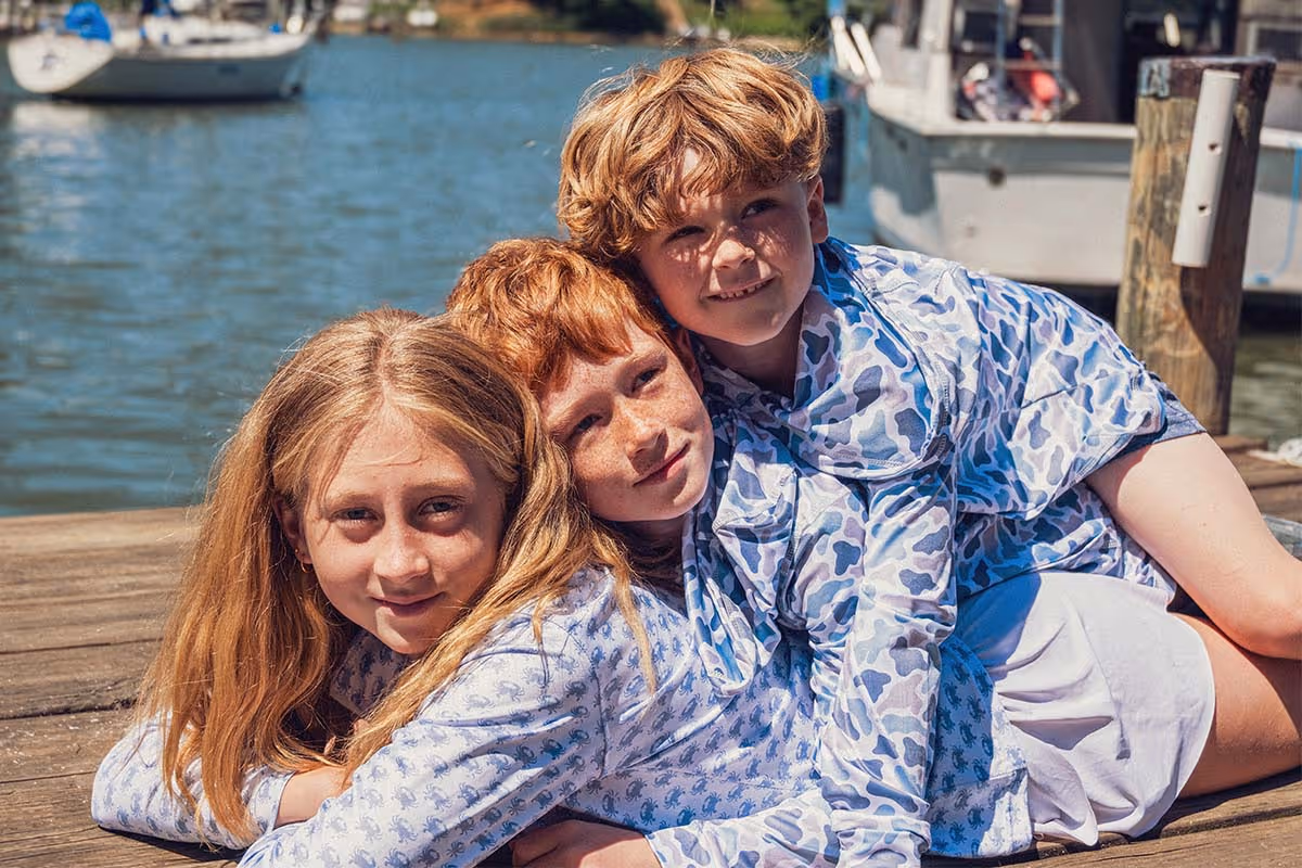 Kids playing and laying on a dock wearing Six Knots Youth Performance Apparel