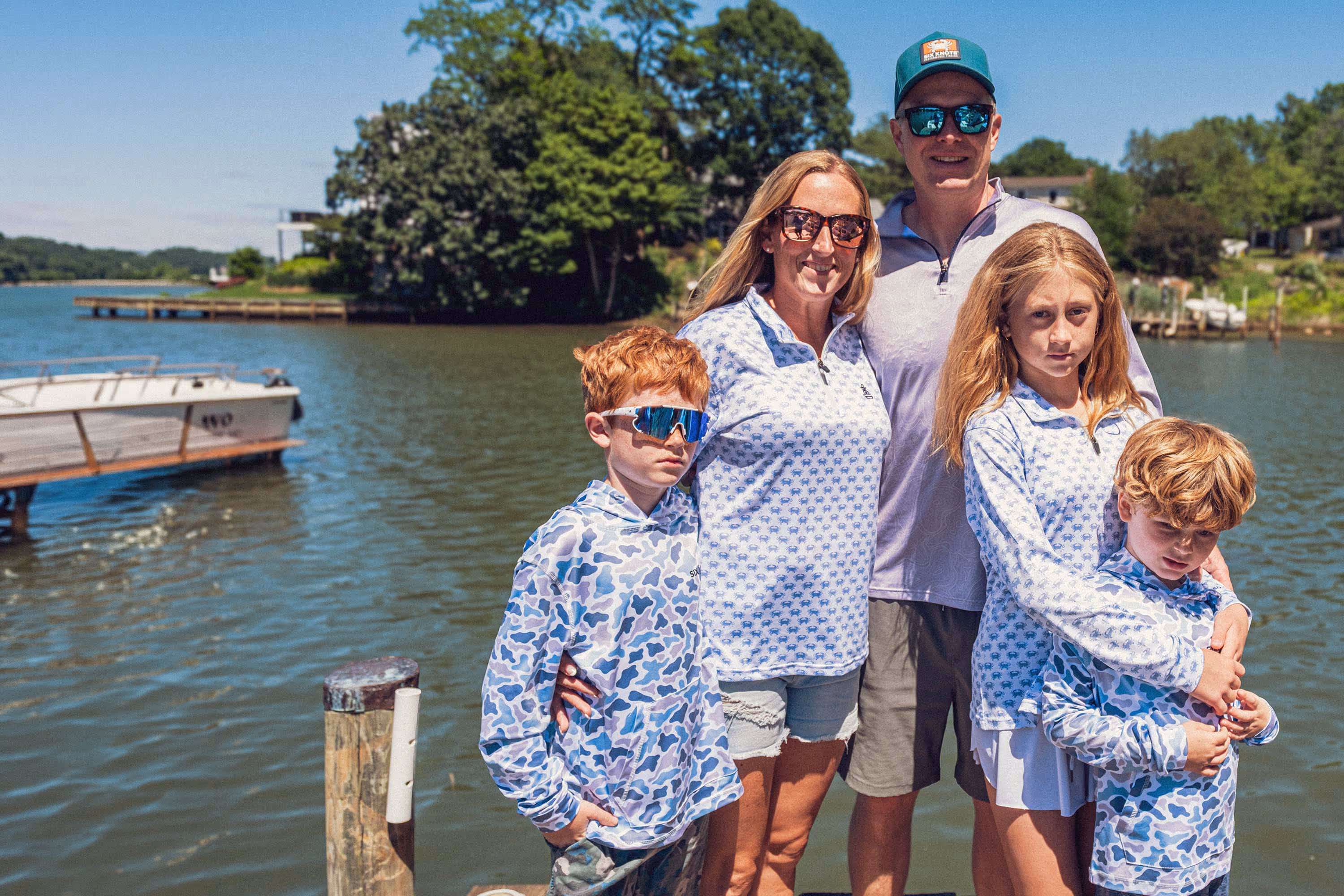 Family wearing Six Knots Performance Apparel standing on a dock in front of the water