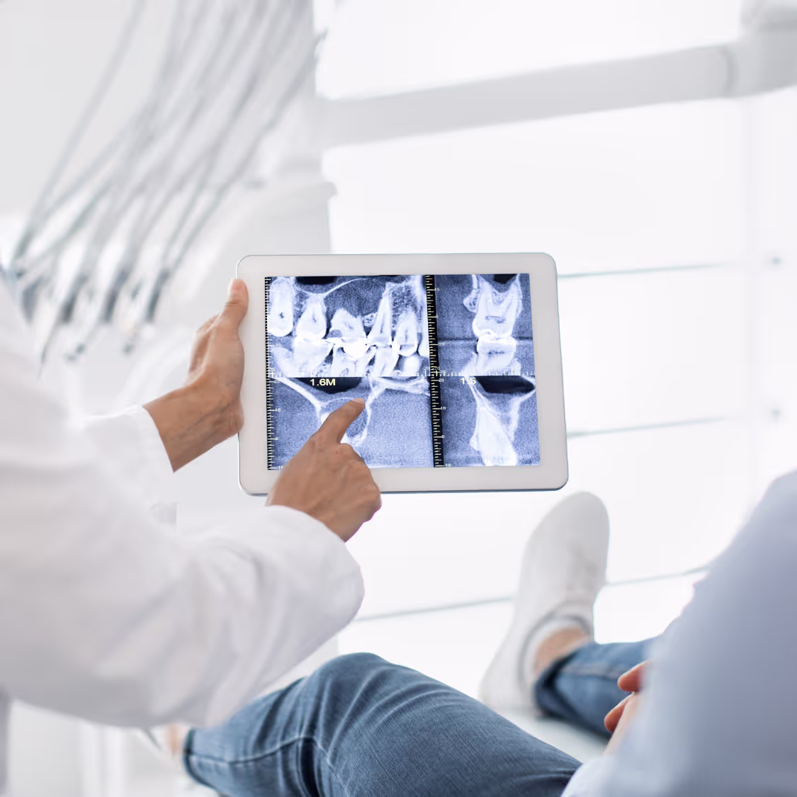 Doctor showing a patient dental X-rays on a tablet screen in a modern medical office, highlighting digital diagnostics in healthcare.