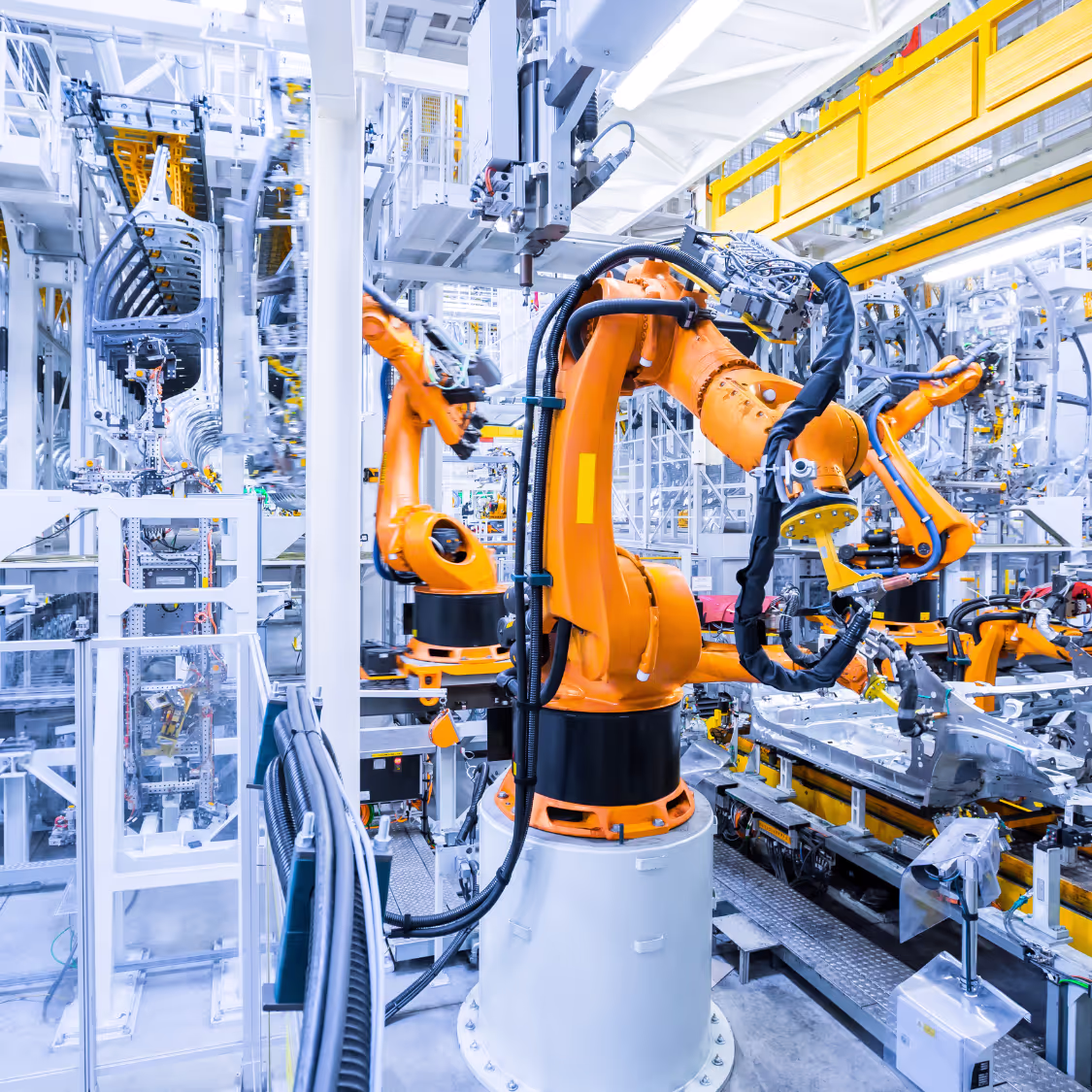 Robotic arms in a high-tech manufacturing facility assembling industrial components with precision automation.
