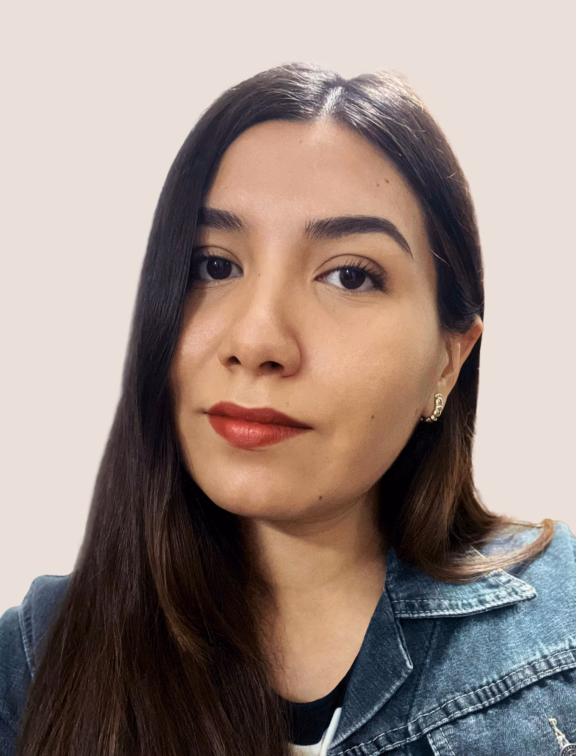 Close-up portrait of a woman with long dark hair wearing red lipstick, gold earrings, and a denim jacket.