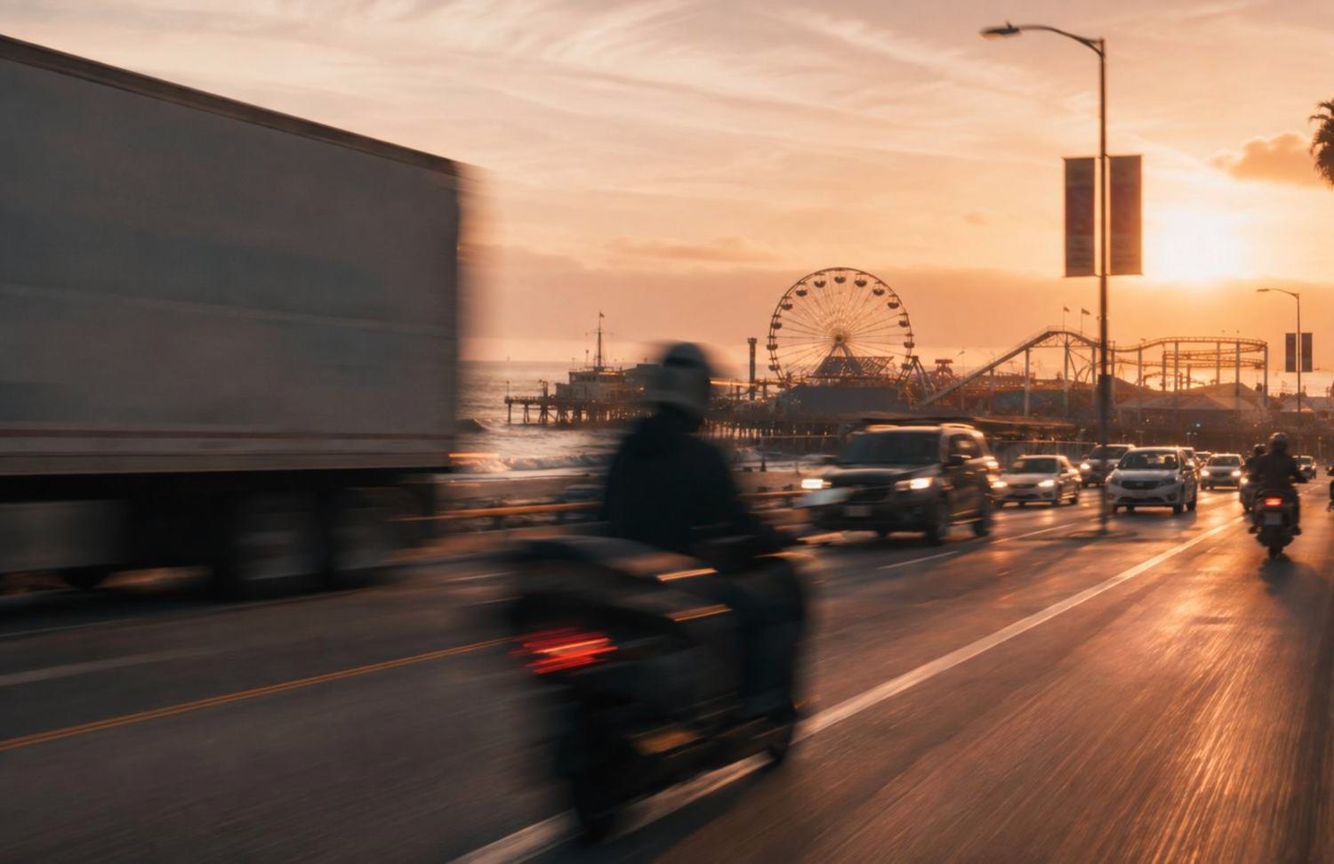 Traffic and motorcycles on a coastal road at sunset, a pier and Ferris wheel in the haze
