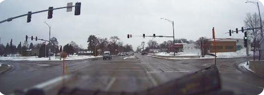 Snowplow dash cam view of an intersection with no snow on the road