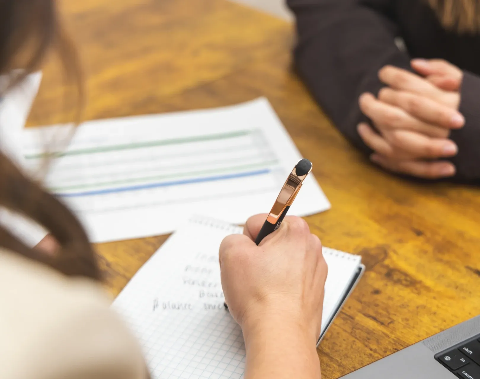 bookkeeper writing on a pad of paper with pen