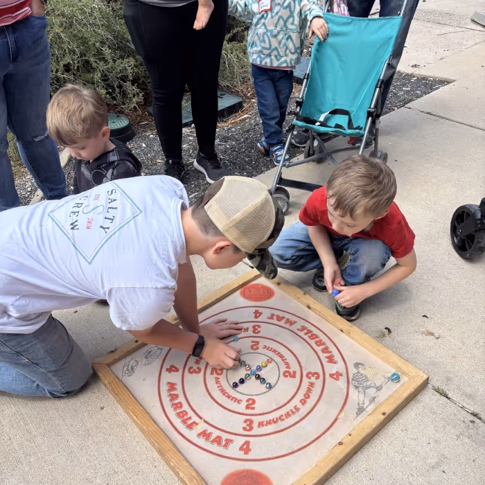 Young boys playing a game on the sidewalk. 