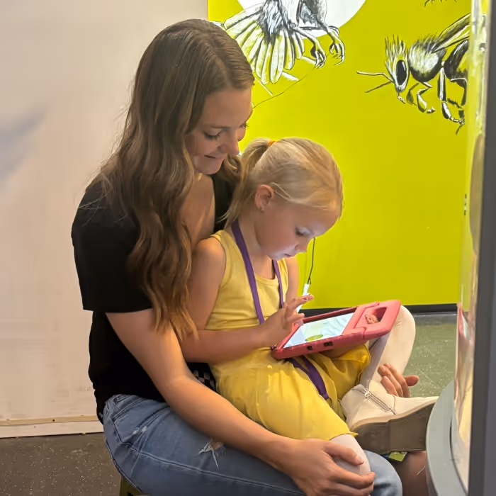 child with tablet in adults lap. 