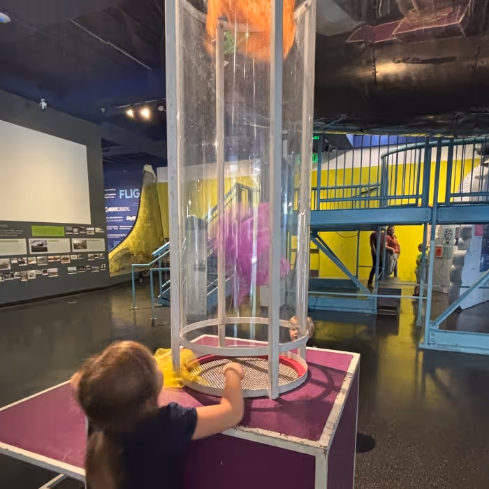 Young child playing with air-powered exhibit at museum. 