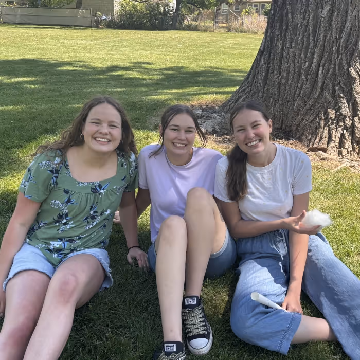 three girls sitting together outside. 