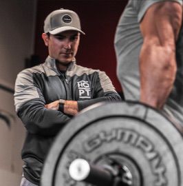 A man standing next to a barbell in a gym.