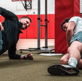 Two men doing push ups in a gym.