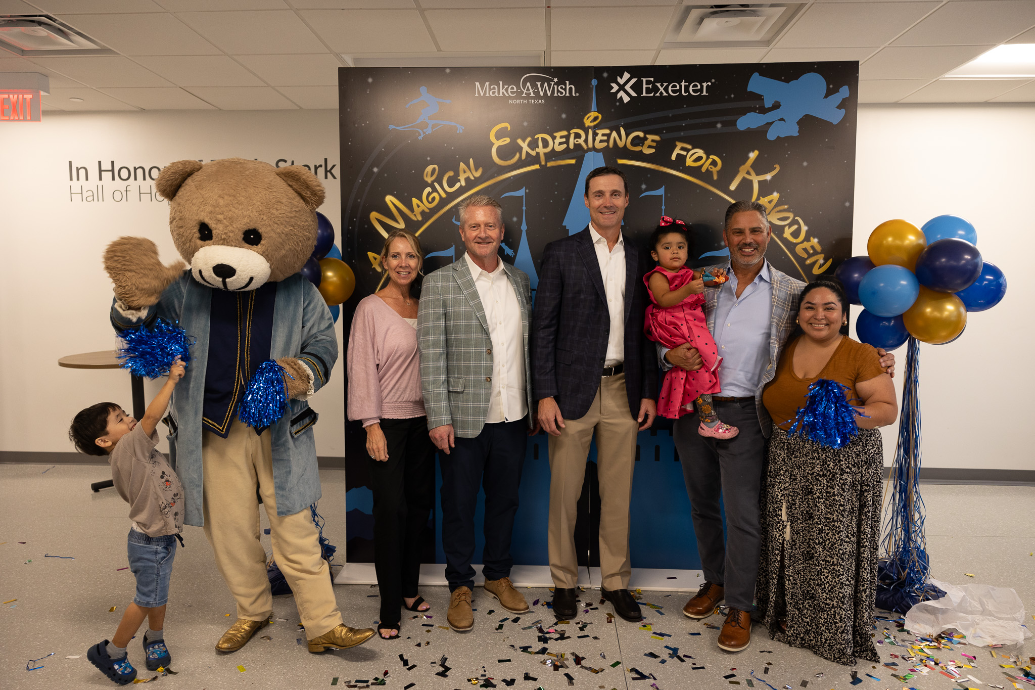 Exeter employees posing in front of a Make-A-Wish photo backdrop
