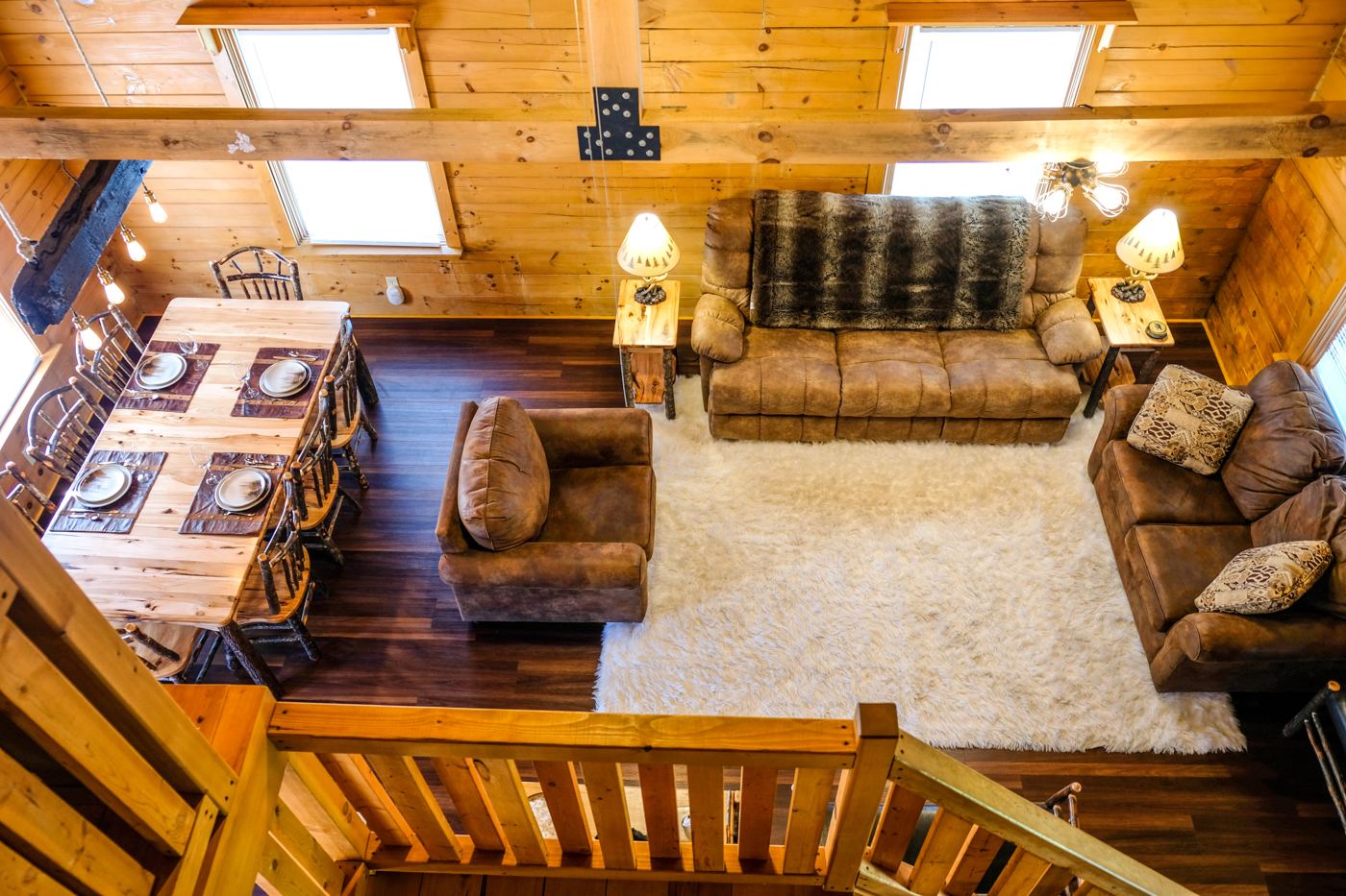 Living room at Deer Creek Cabin seen from the loft, with log walls and sofas