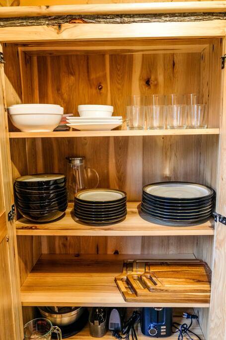 Kitchen cabinet stocked with dishes, glasses, cookware and small appliances