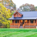 Deer Creek Cabin log cabin exterior with front porch, surrounded by autumn trees