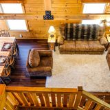 Living room at Deer Creek Cabin seen from the loft, with log walls and sofas