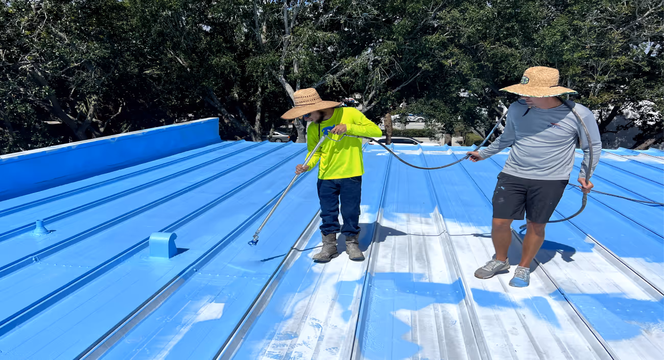 worker applying blue roof coating to a metal roof