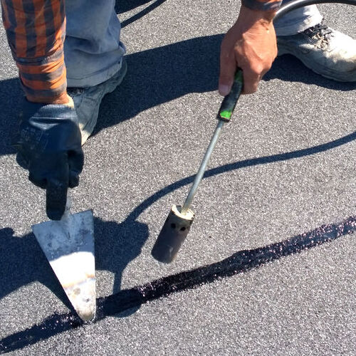 A Roofer Seals a Seam on a Flat Roof.