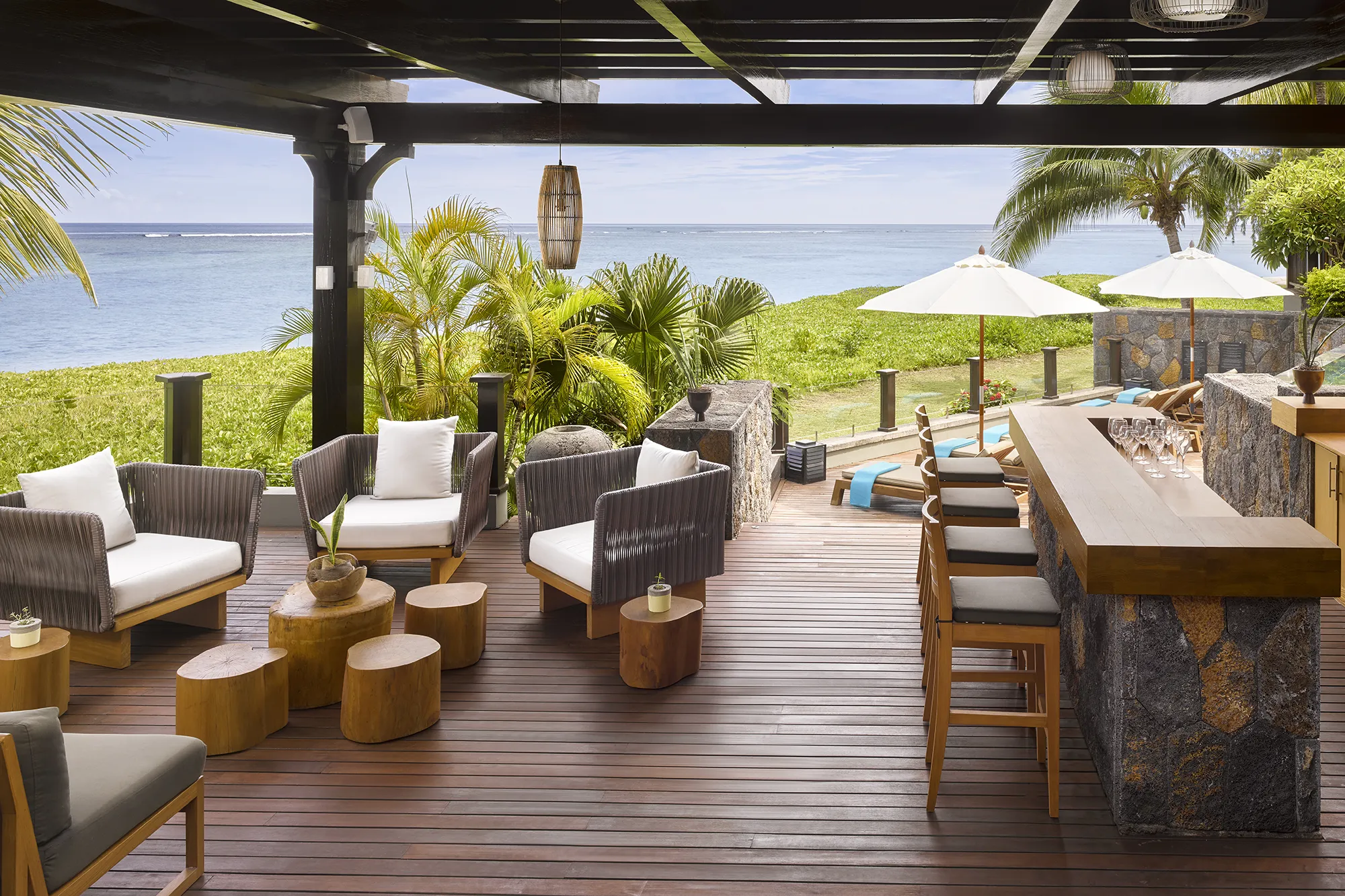 Lounge med bar och fåtöljer på ett trädäck med utsikt över havet