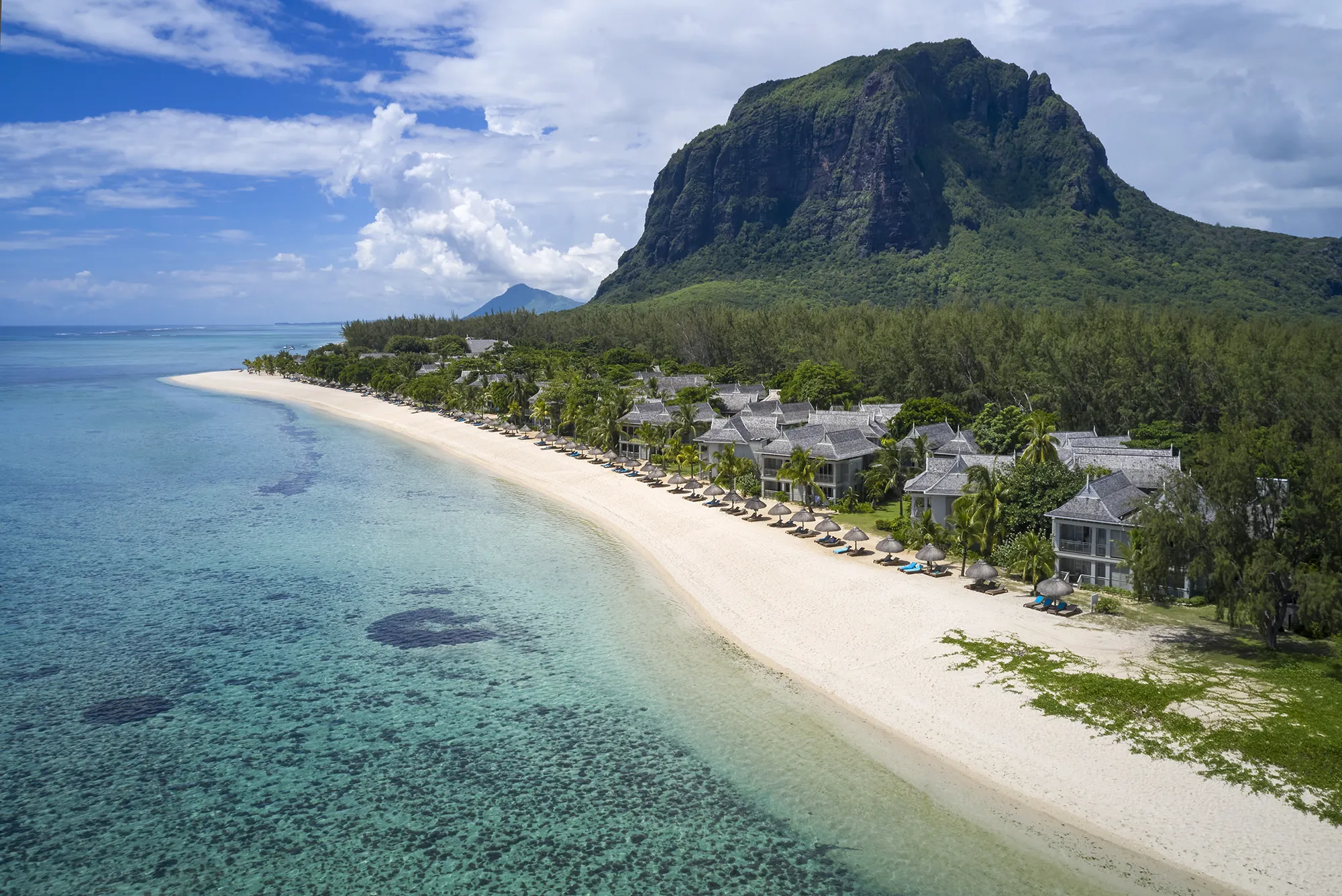 Flygbild över en lång vit sandstrand och turkos lagun med Le Morne-berget i bakgrunden
