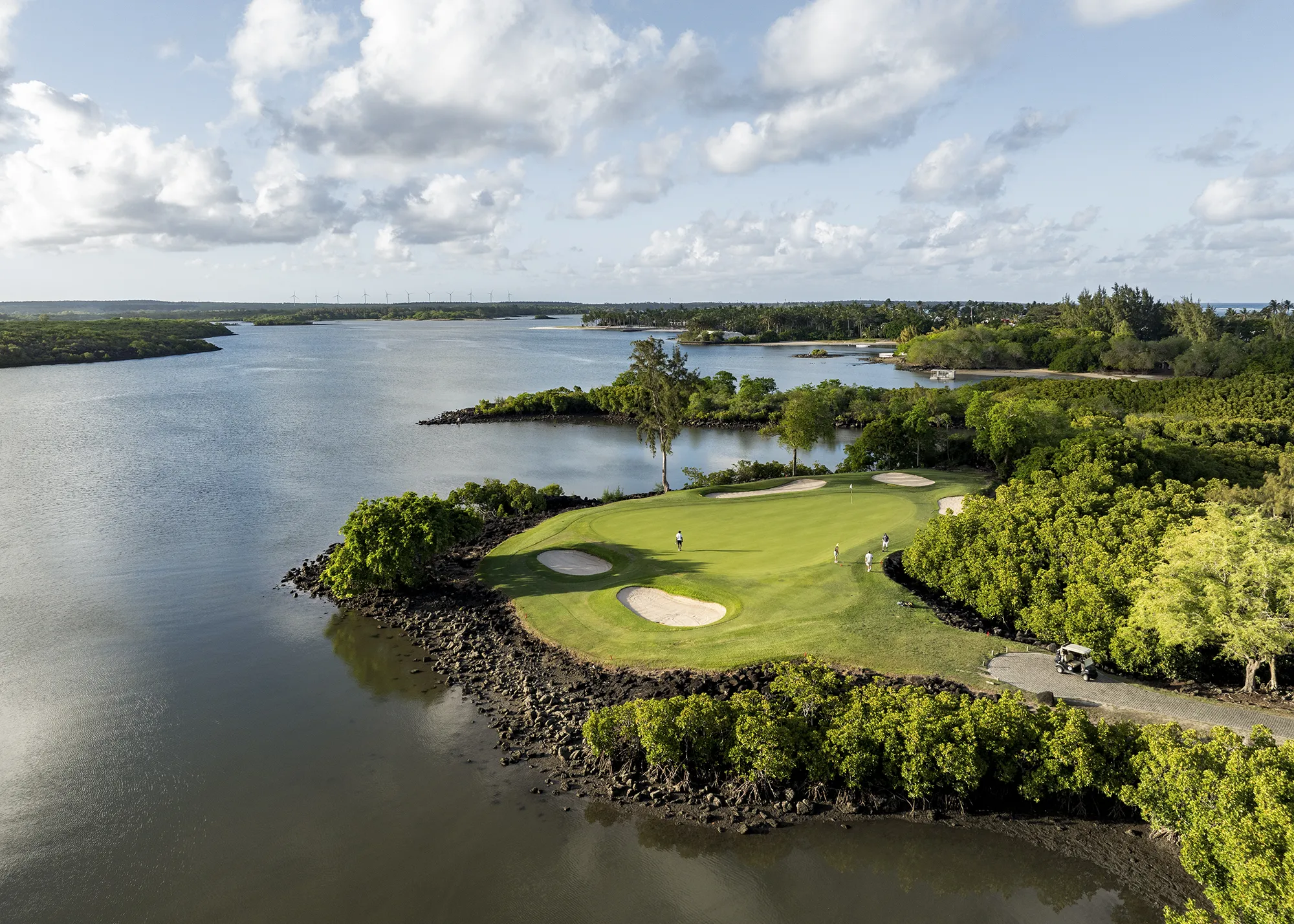 Golfgreen på en udde omgiven av vatten och grönska