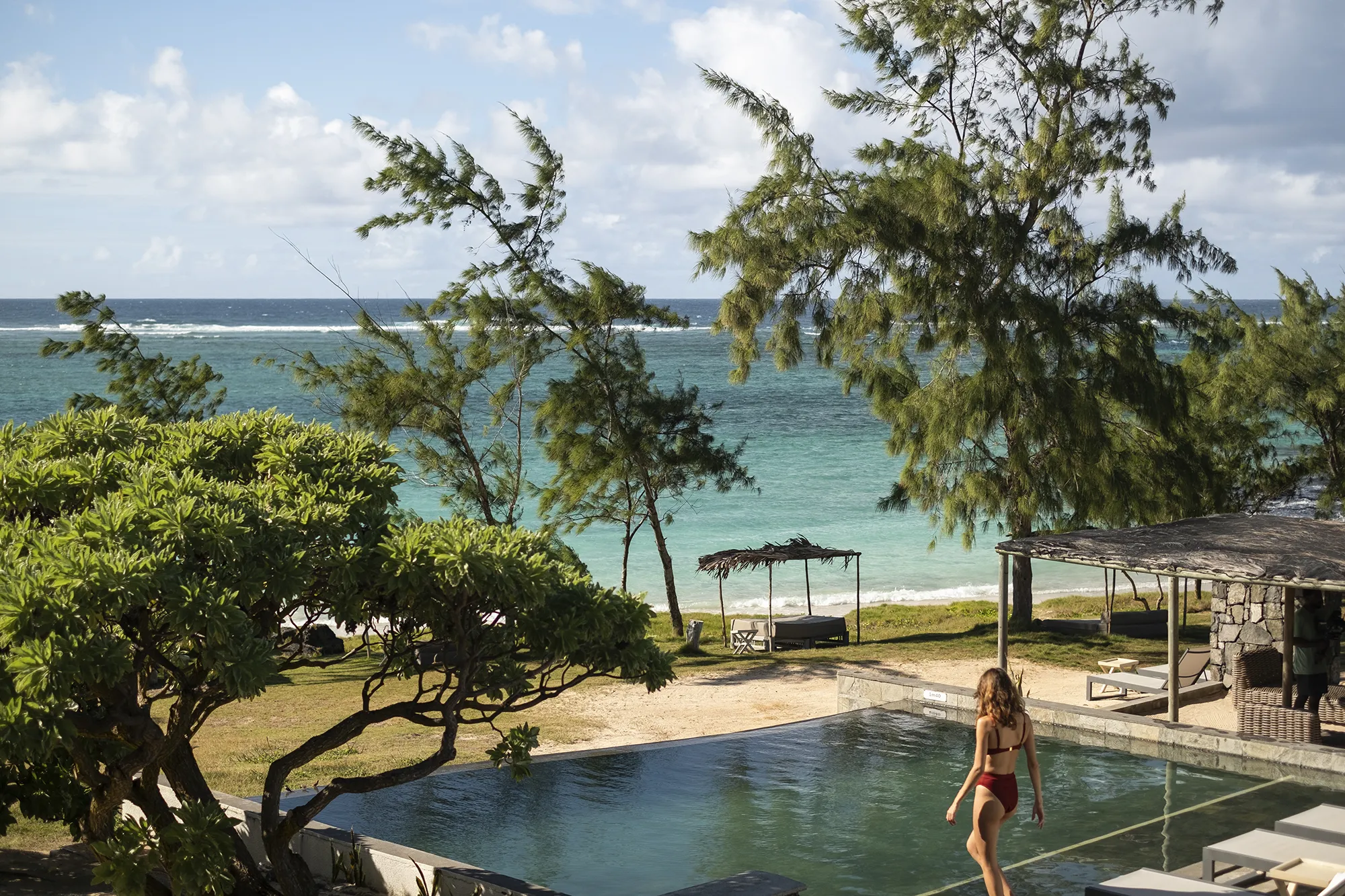 Infinitypool bland träd med utsikt över stranden och det turkosa havet