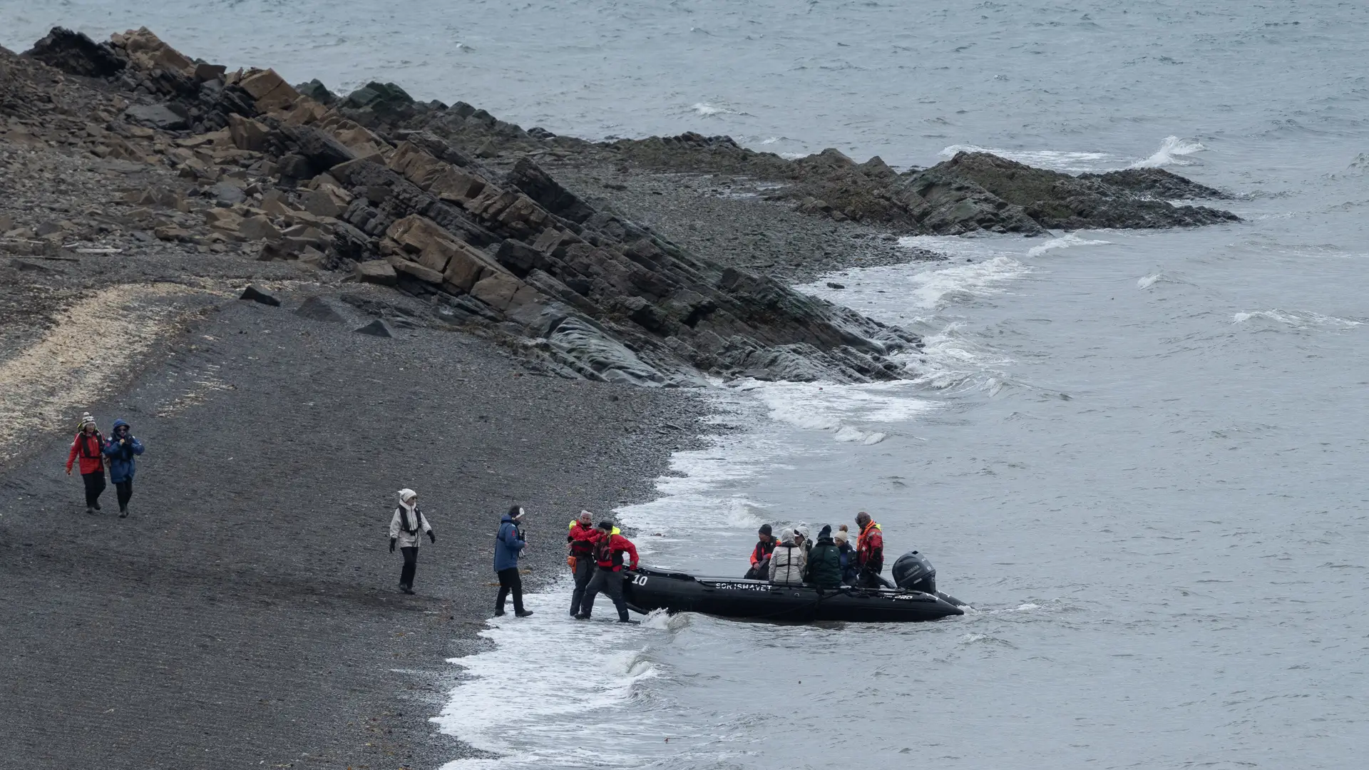 Landstigning på Svalbard från en gummibåt, där flera äventyrare stier i land.
