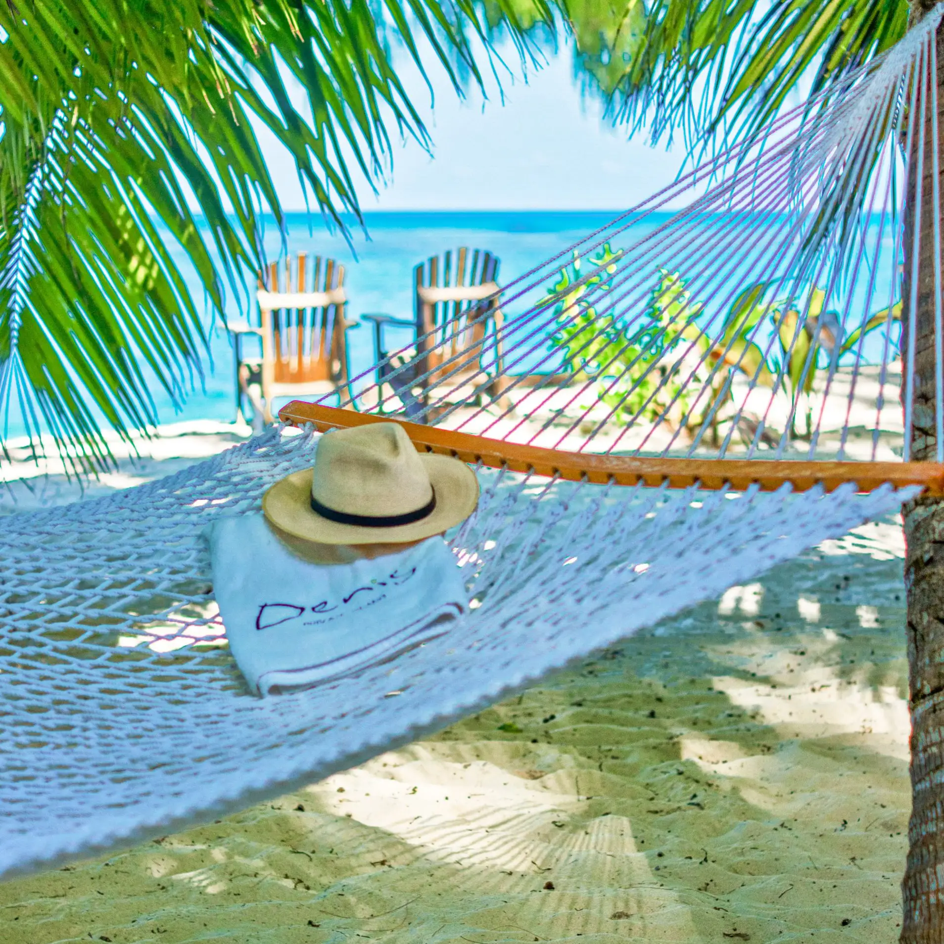 En hatt och en handduk i en hängmatta vid en strand på Seychellerna.