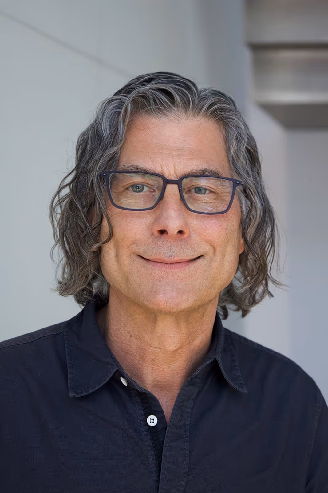 Professional headshot of doctor Robert Poe psyd, standing in a bright lobby and looking calmly at the camera.