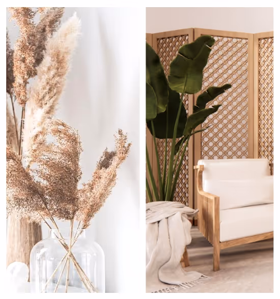 Interior setting with dried pampas grass in a clear glass vase and a wooden armchair with white cushions next to a green leafy plant and a decorative wooden room divider.