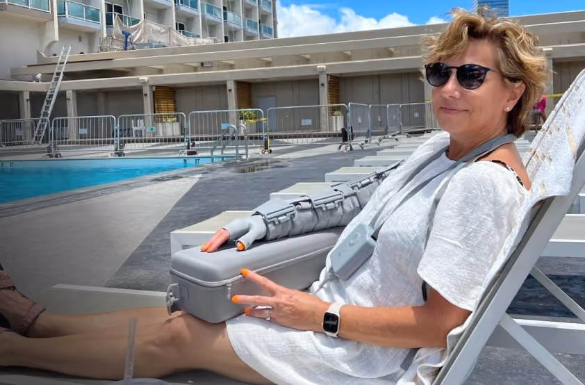 Eileen S. relaxing on a poolside lounge chair while wearing her Dayspring arm garment