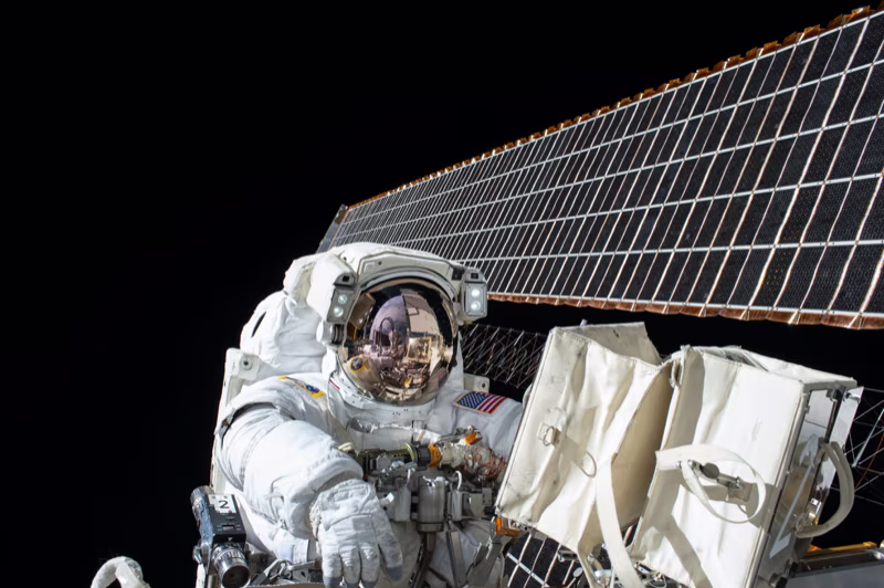 Astronaut in outer space working on a satellite wearing a spacesuit