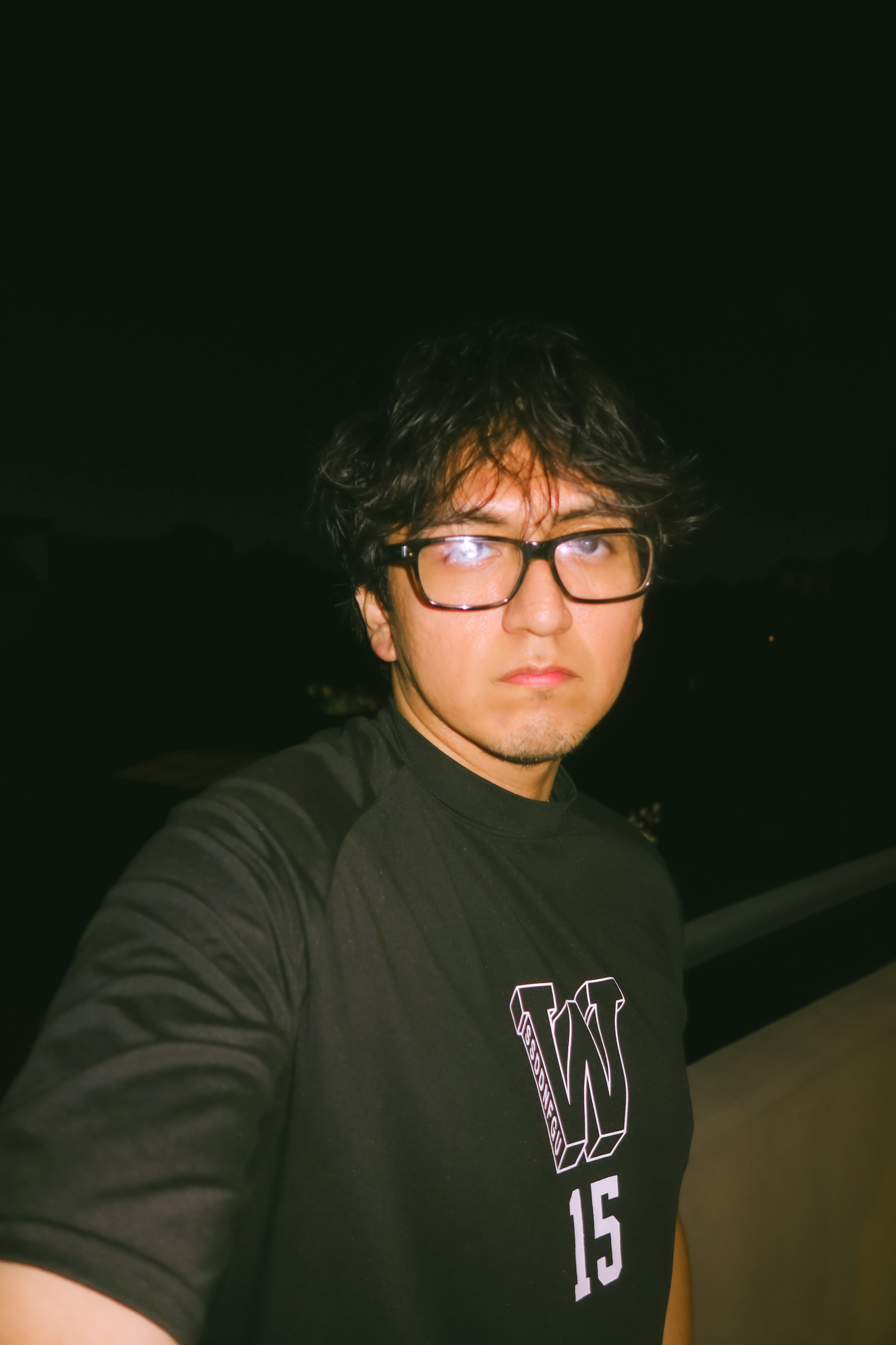 Man with his hands in front of his face wearing rings and an orange sweatshirt.
