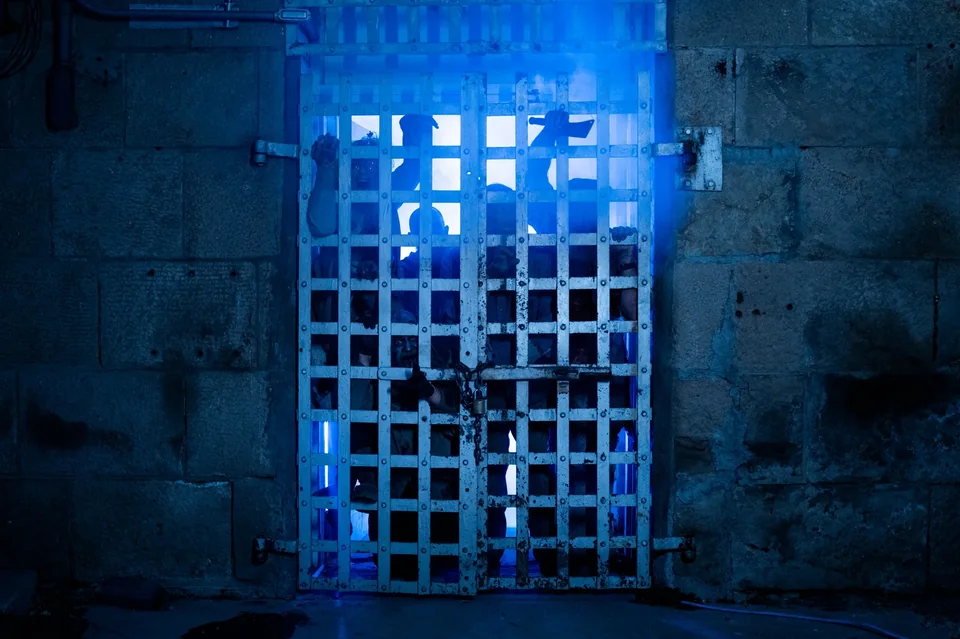A heavy iron entrance glows blue through theatrical fog.