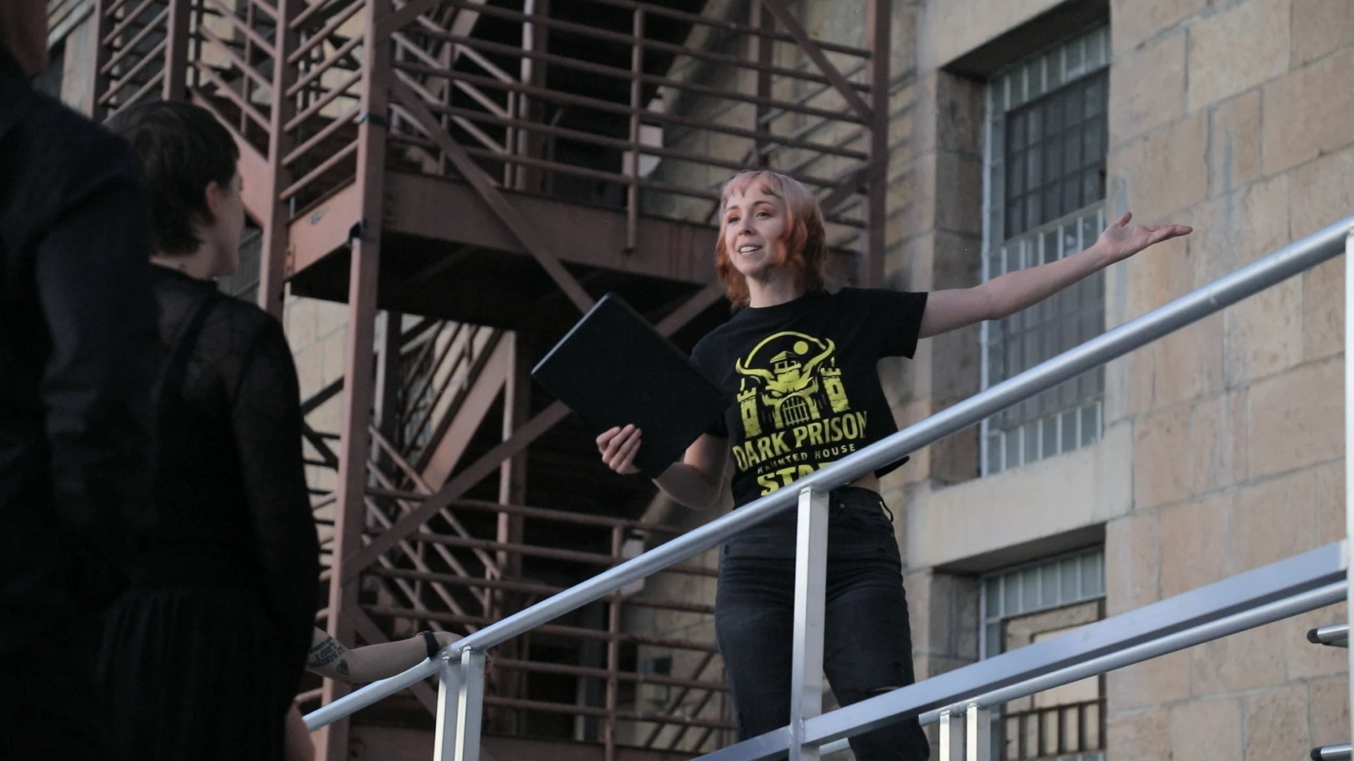 A guide speaking to visitors beside the sandstone stairwell at Nevada State Prison