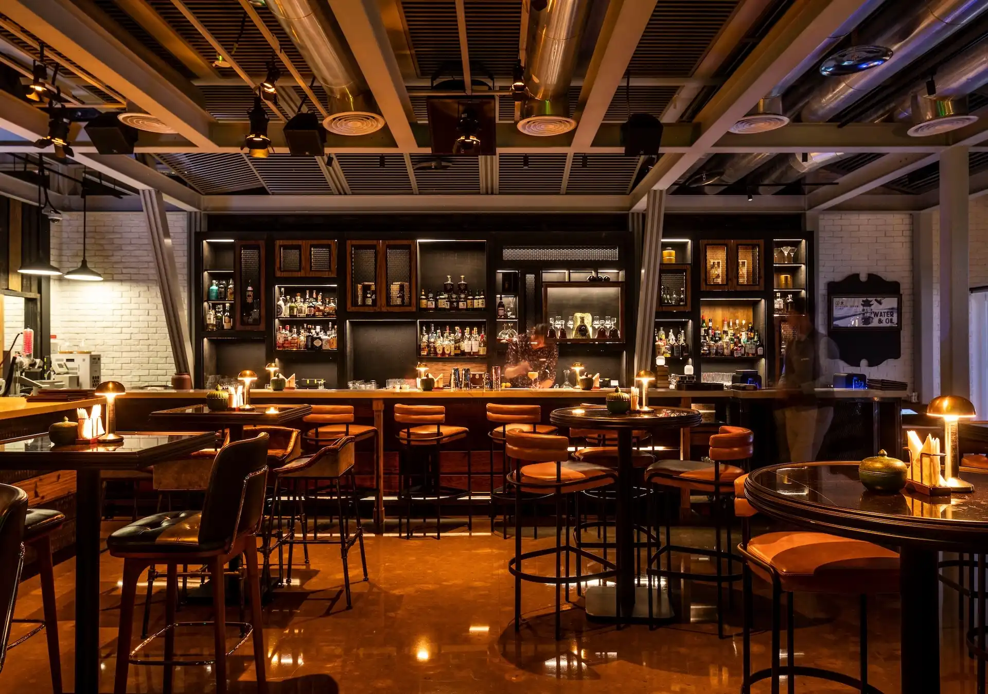 Main bar at Prohibition Bar, Mandarin Oriental Shenzhen, with distressed timber back bar shelving, exposed ductwork and bar stools