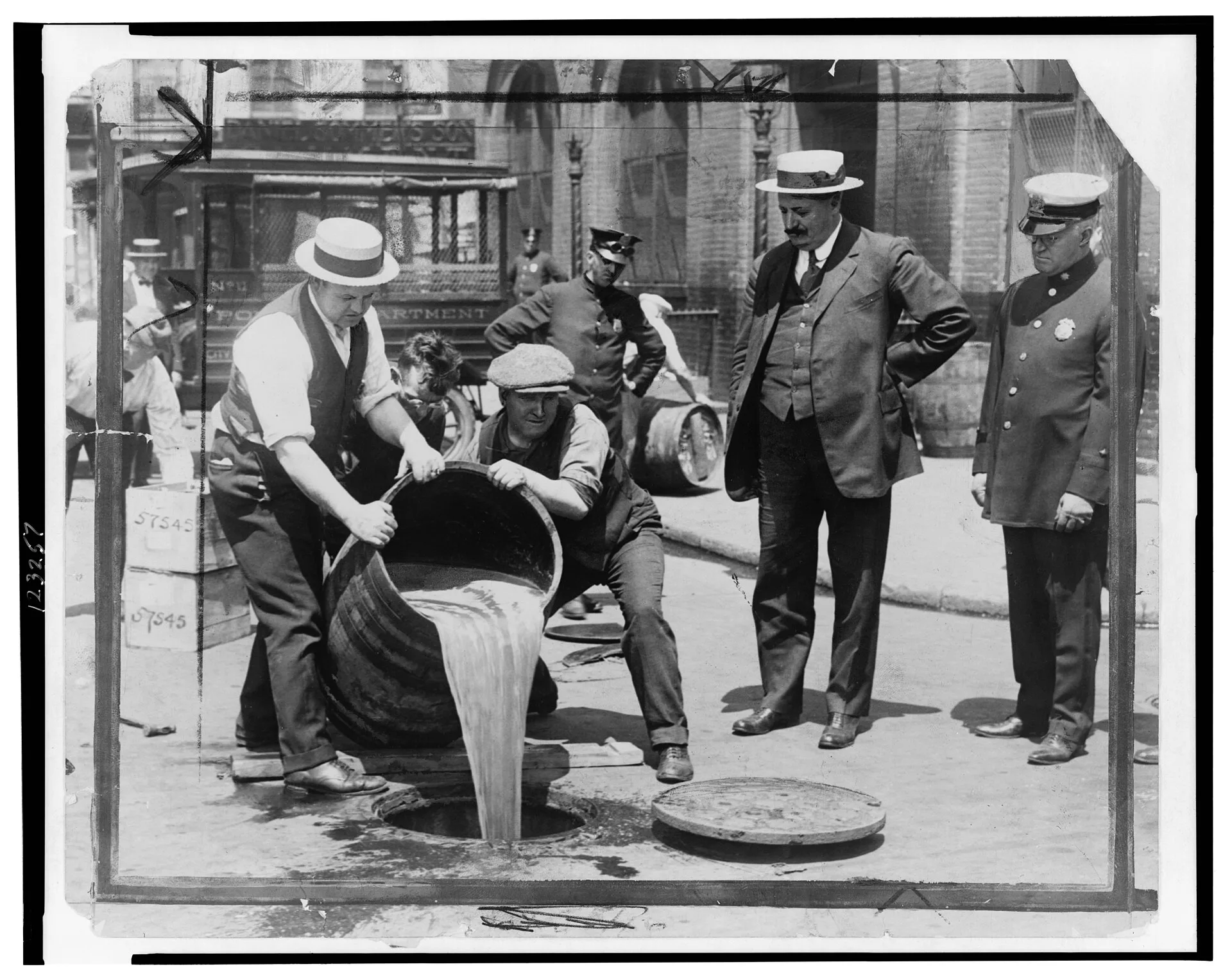 Prohibition agents pouring seized liquor into a New York sewer