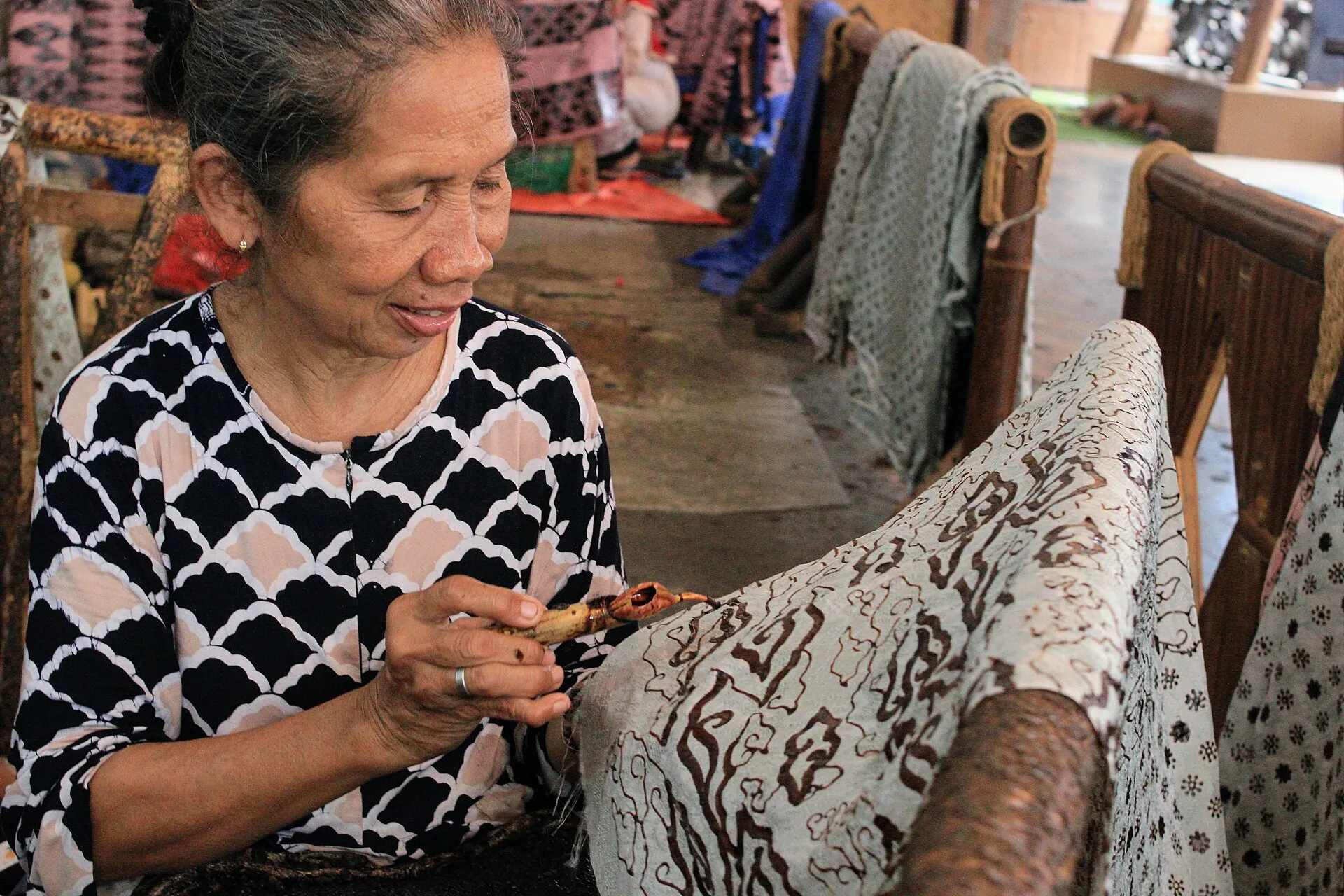 Artisan applying hot wax to cloth with a canting