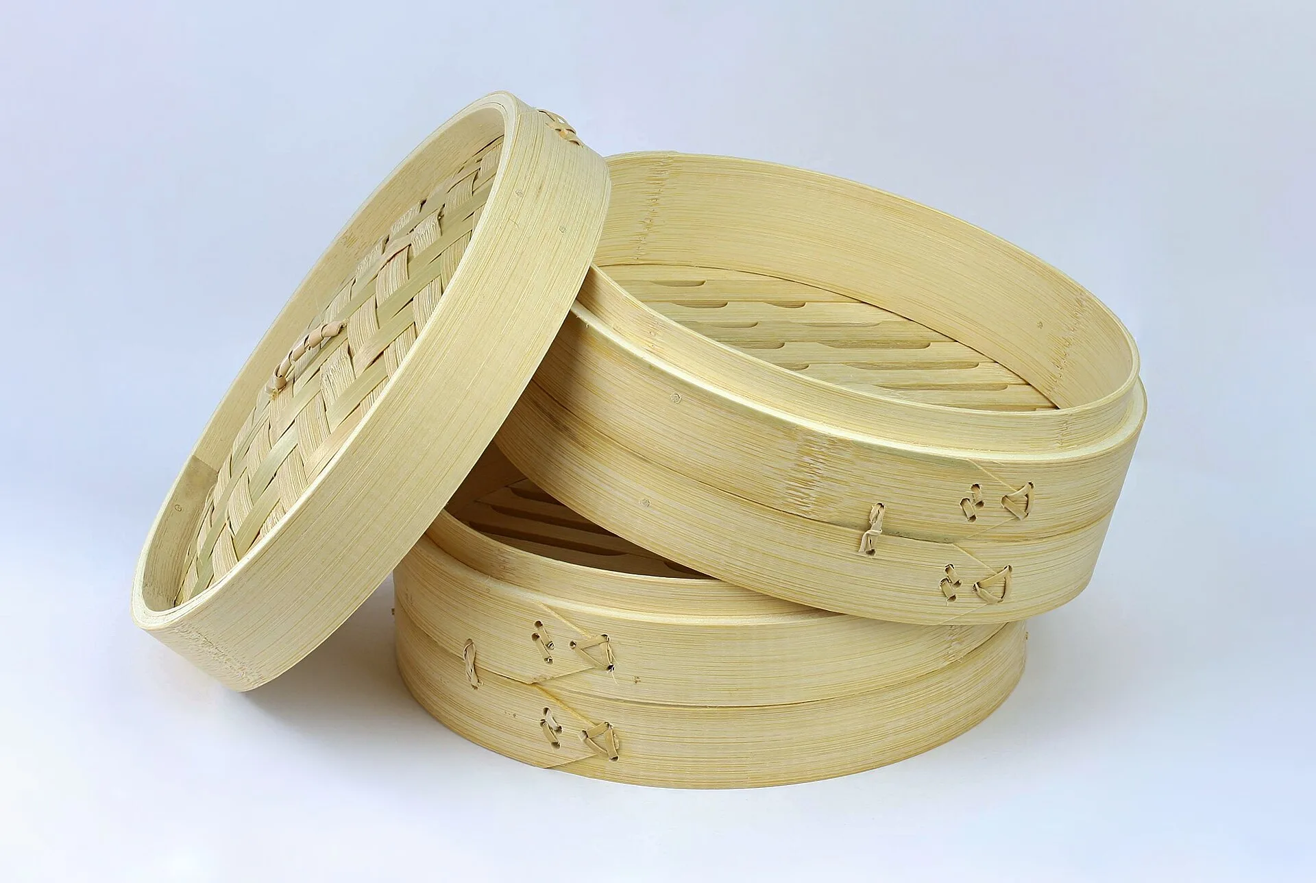 Stacked round bamboo steamer baskets with a woven lid