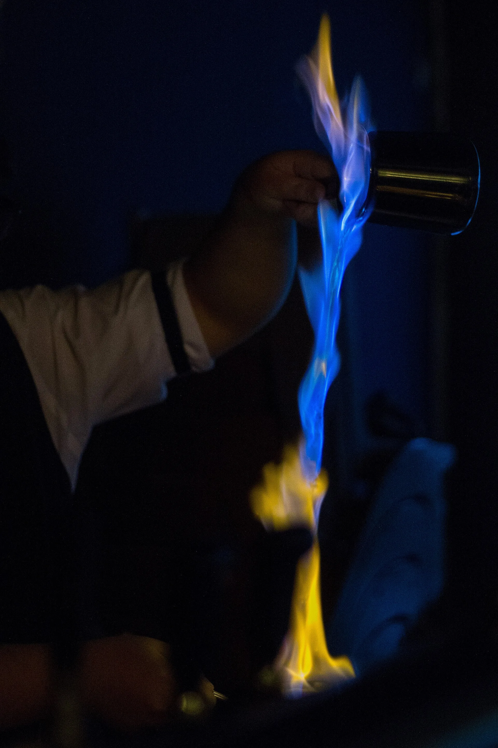Flaming whisky poured between two metal mugs to make a Blue Blazer