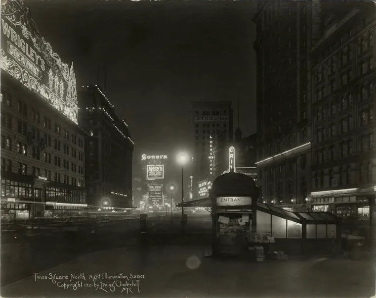Night view of Times Square in 1921 with illuminated signs and a subway kiosk