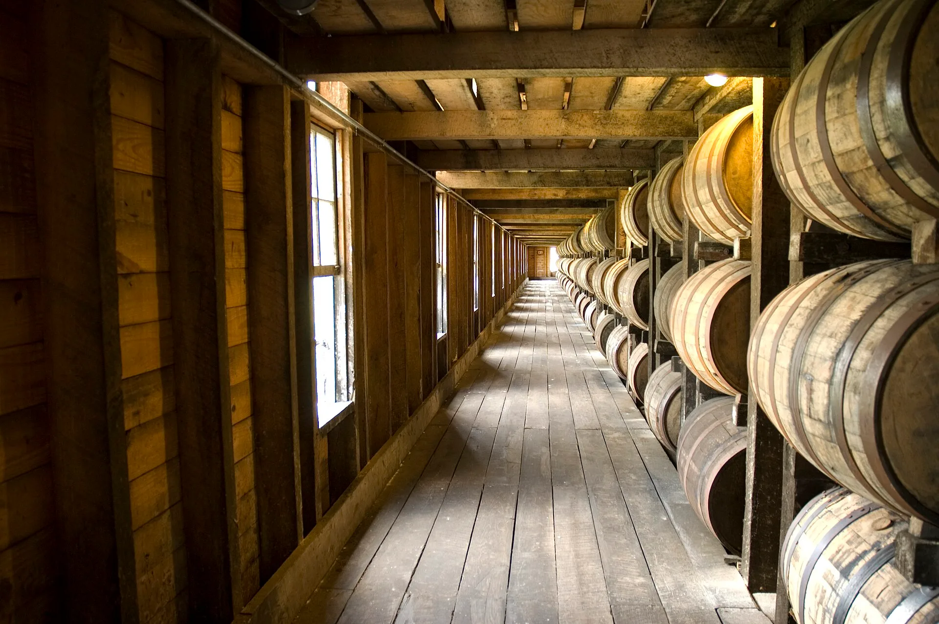 Rows of wooden bourbon barrels stacked in a Kentucky ageing warehouse