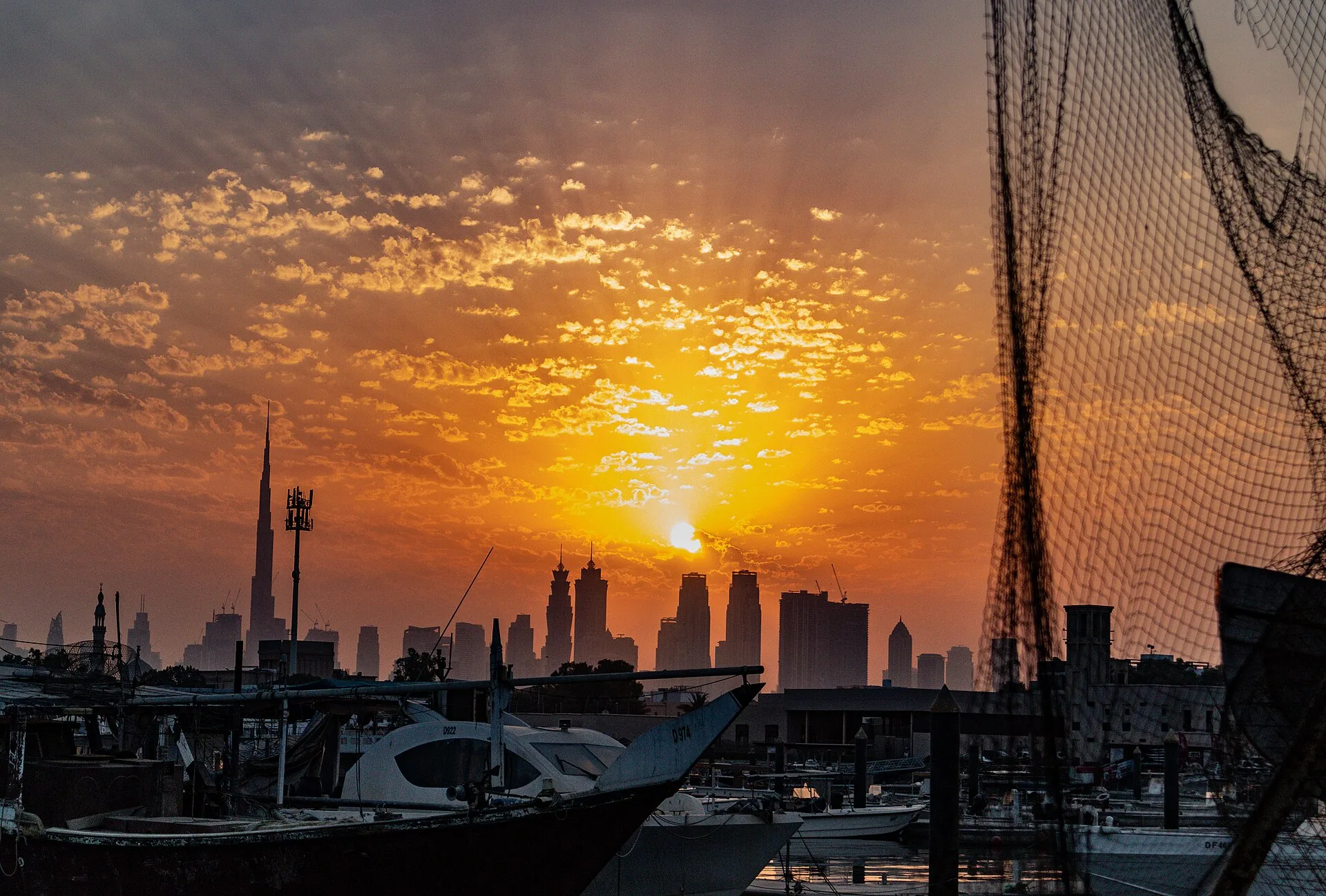 Fishing boats in Umm Suqeim port, Dubai, at sunrise with towers on the skyline