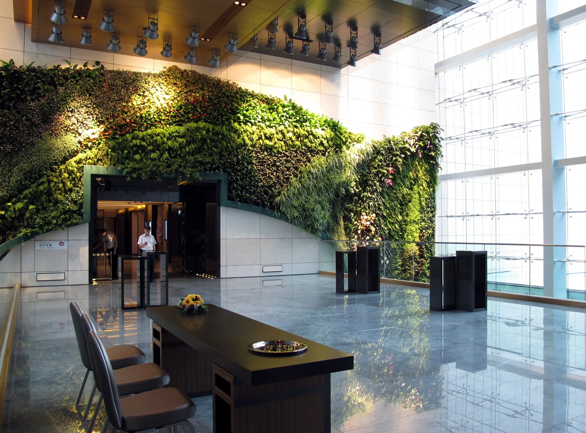 Hotel lobby with a large planted wall, glass facade and reception desk