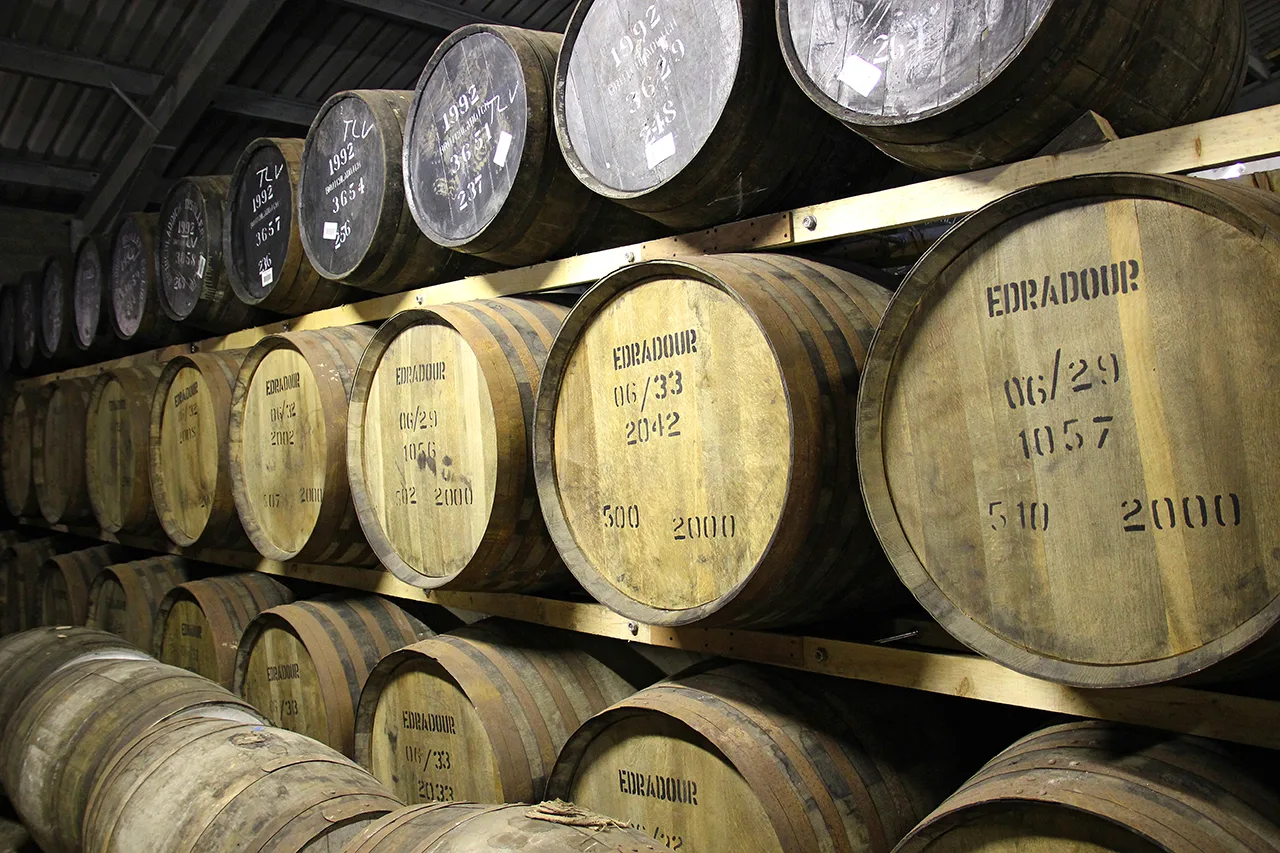 Rows of whisky casks stacked on racks in a distillery warehouse