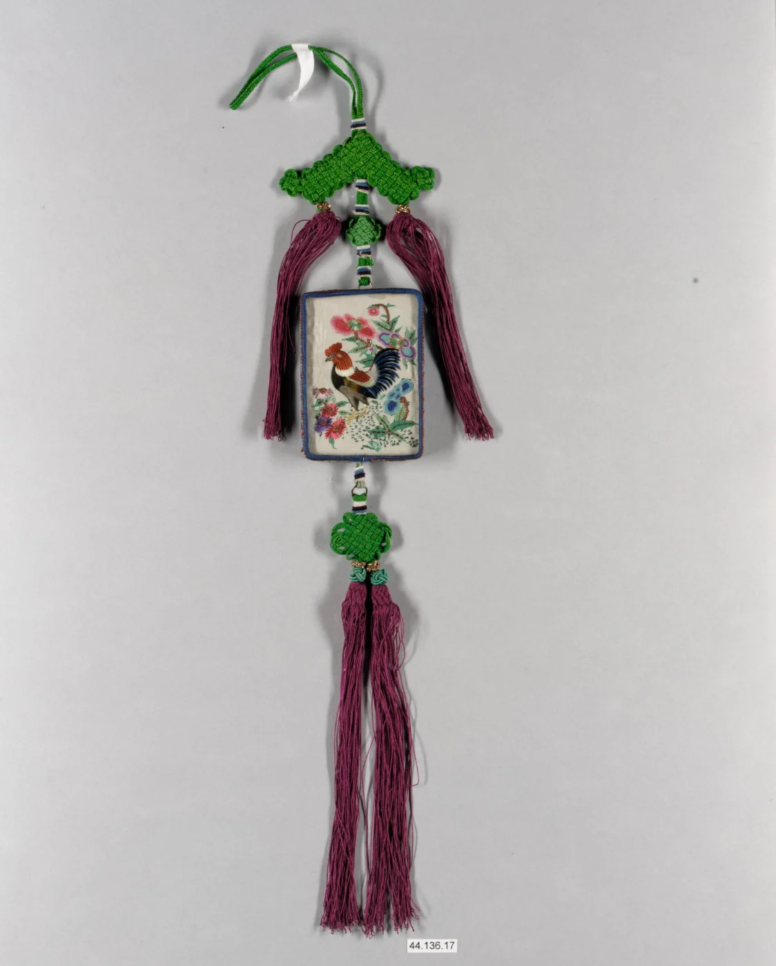 Embroidered Chinese mirror case hanging from green knotted cords with purple tassels