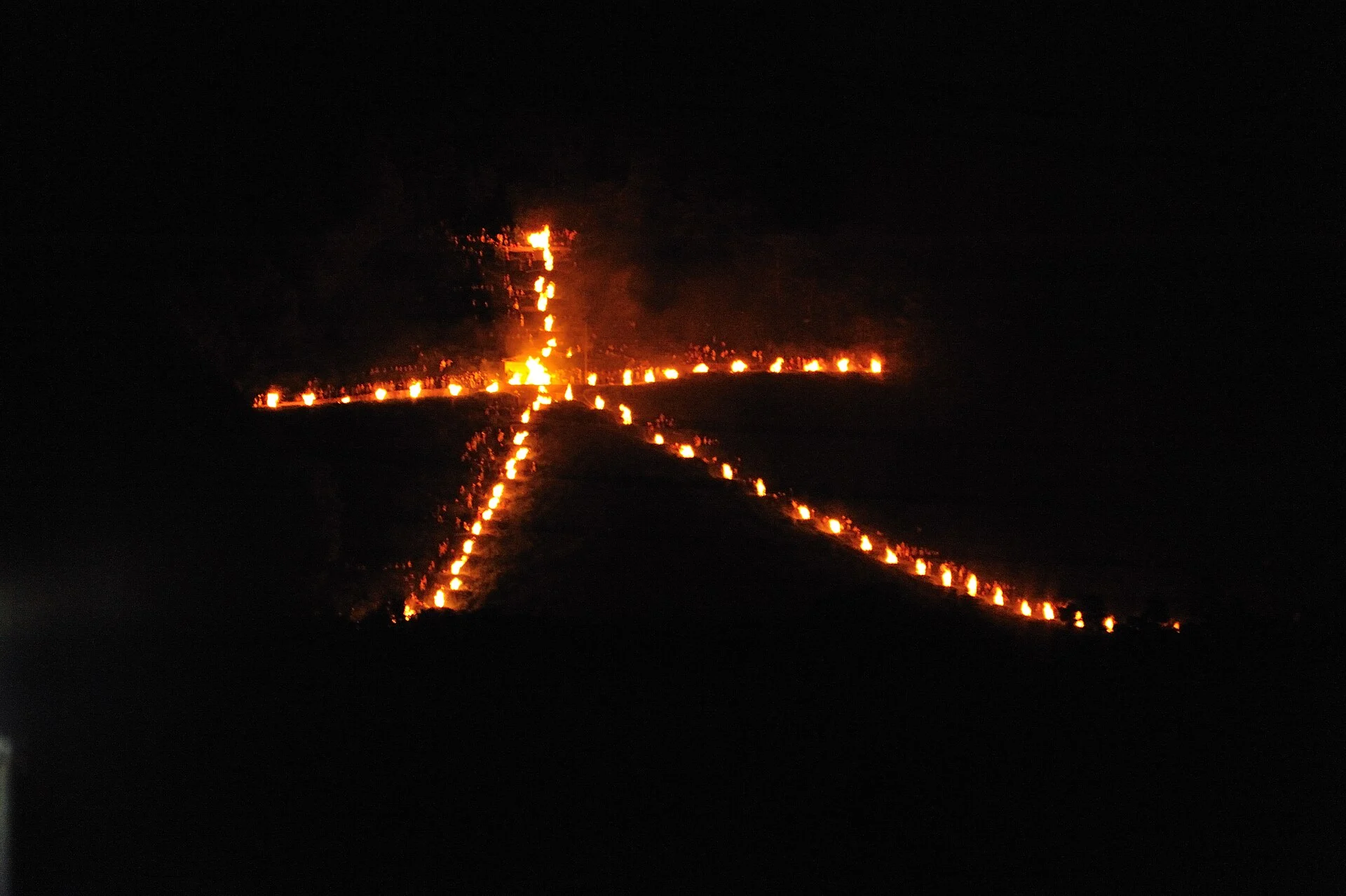 The character dai outlined in fire on a dark hillside at night