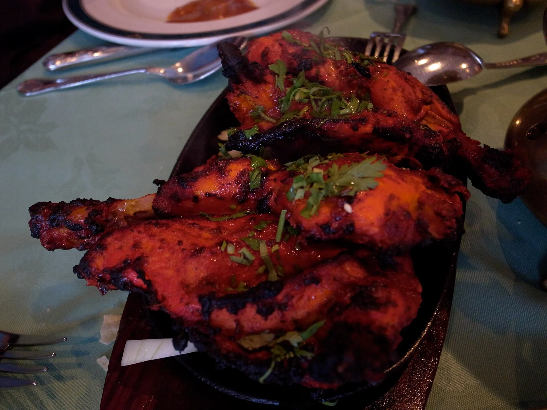 Plate of red-spiced tandoori chicken pieces with herbs