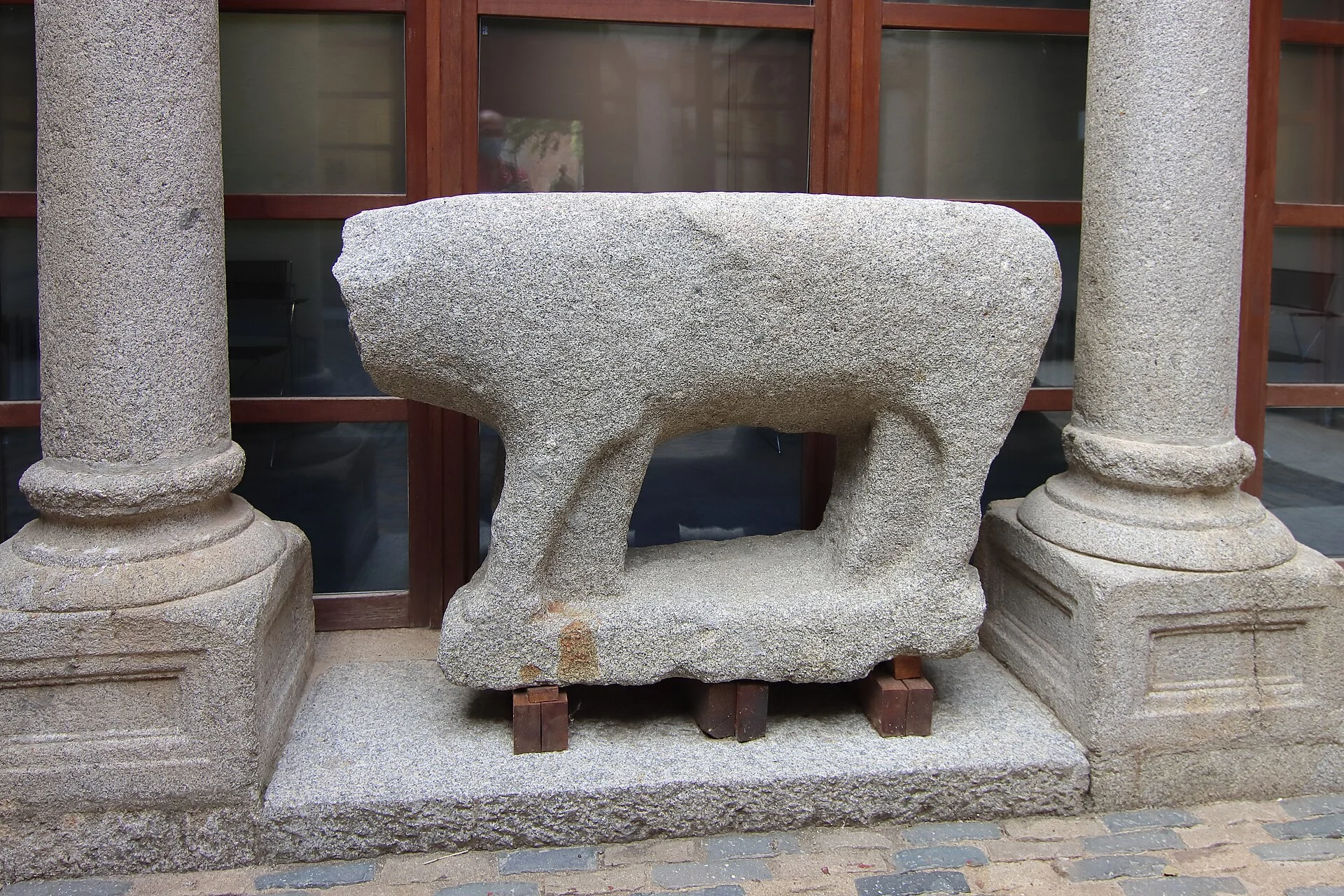 Granite verraco sculpture of a boar or bull between stone columns