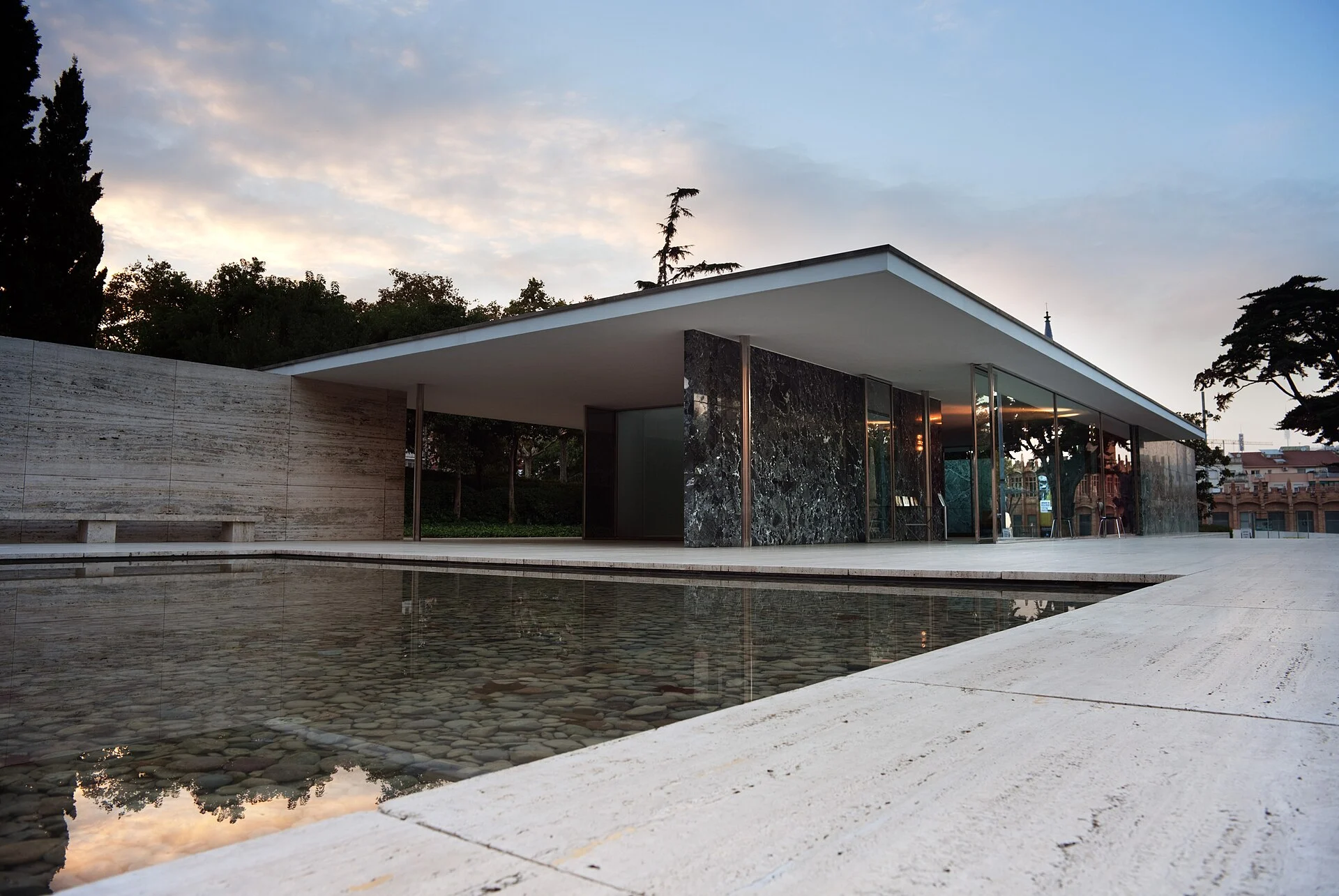 Flat-roofed Barcelona Pavilion with glass walls beside a reflecting pool